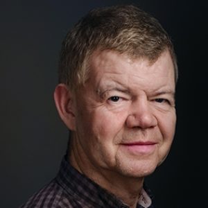 A Portrait of Redmond Smiling on a Dark Background